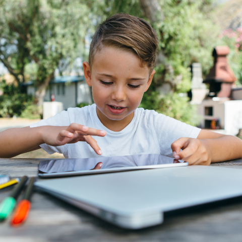 Boy counting along with a tablet outdoors